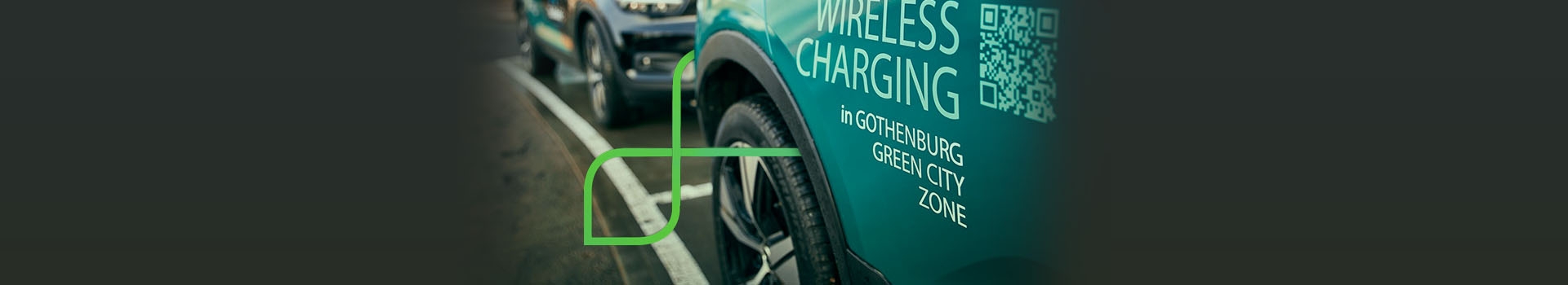 Segue Dé     Close em lateral de carro estacionado sobre marcação em linha branca no solo. Na porta do automóvel lê-se em letras garrafais: 'Wireless Charging'. Logo abaixo, em letras menores, lê-se 'in Gothenburg Green City Zone'. Ao fundo, outro carro do mesmo modelo estacionado.